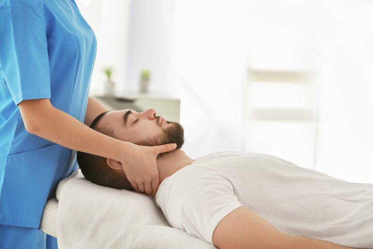 A chiropractor gently adjusts a person's back in a brightly lit clinic.